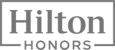 The image shows the logo of "Hilton Honors," a loyalty program by Hilton Hotels & Resorts, featuring a gray text design inside a rectangular border.