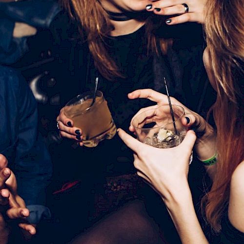 People are socializing and enjoying drinks at what looks like a club or bar. They are engaged in conversation and appear to be having a good time.