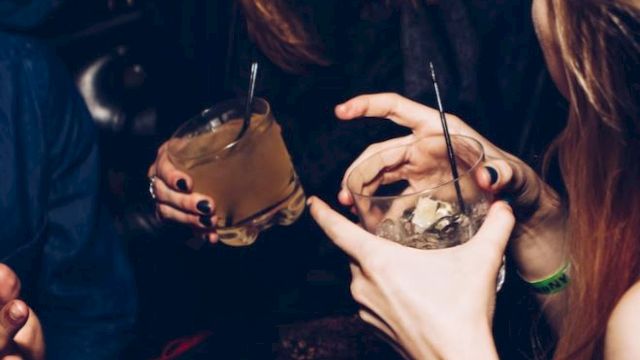 People are socializing and enjoying drinks at what looks like a club or bar. They are engaged in conversation and appear to be having a good time.