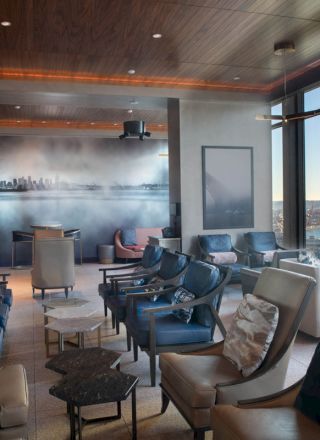 A modern, comfortable lounge with large windows offering a scenic waterfront view. It features ample seating and stylish decor.